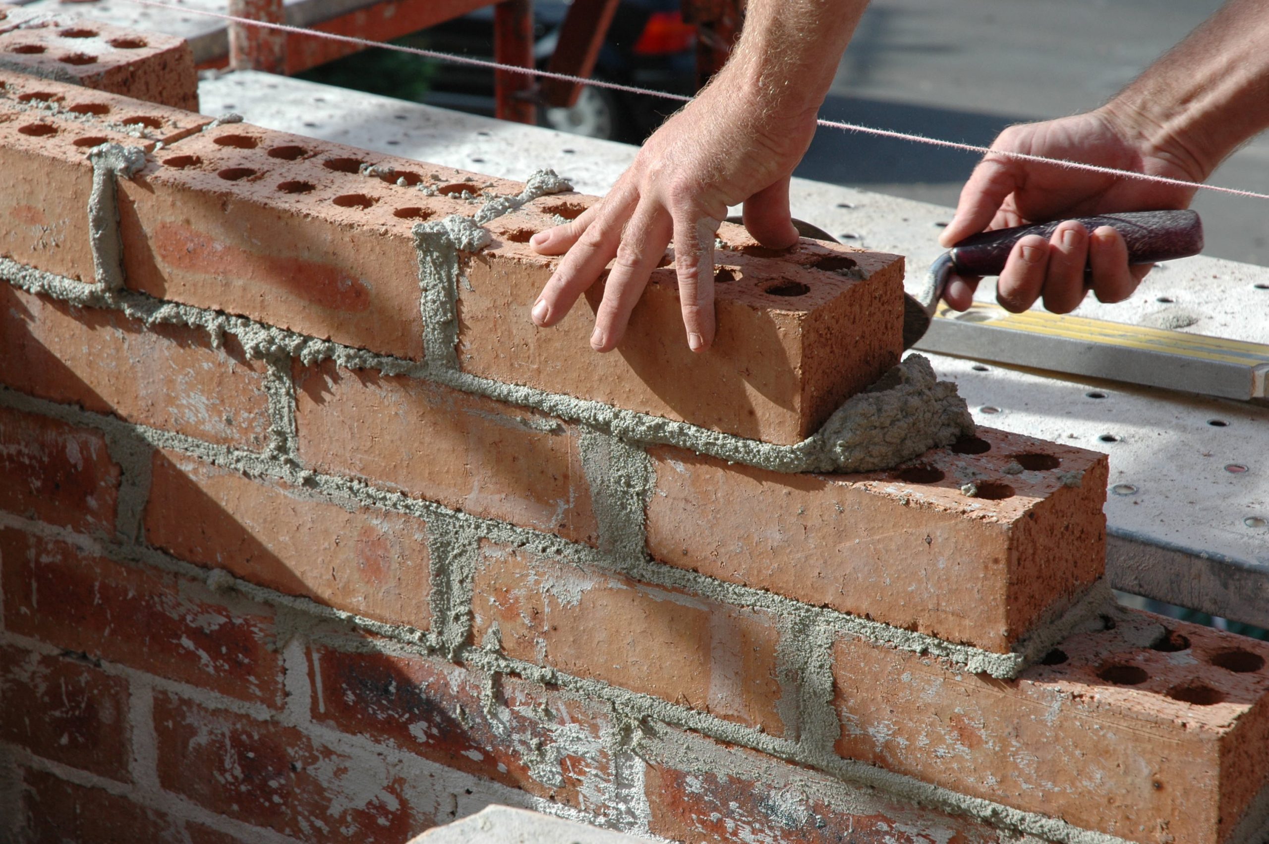 hands of a bricklayer laying bricks with a trowel