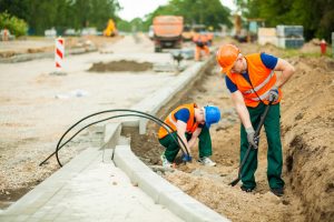 two construction workers working on site building a road