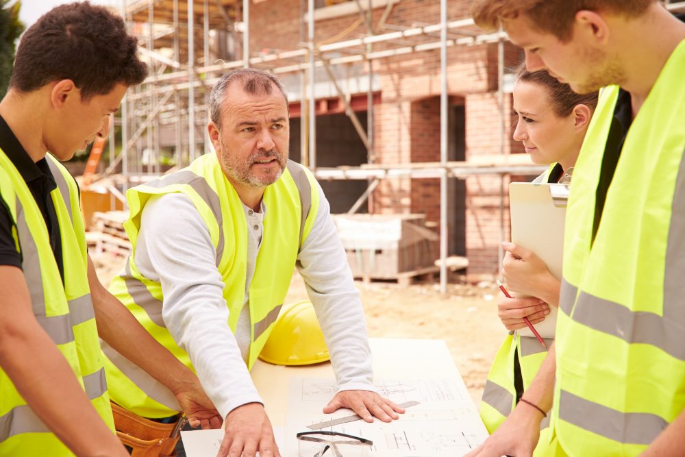 four workers on a builiding site looking at plans