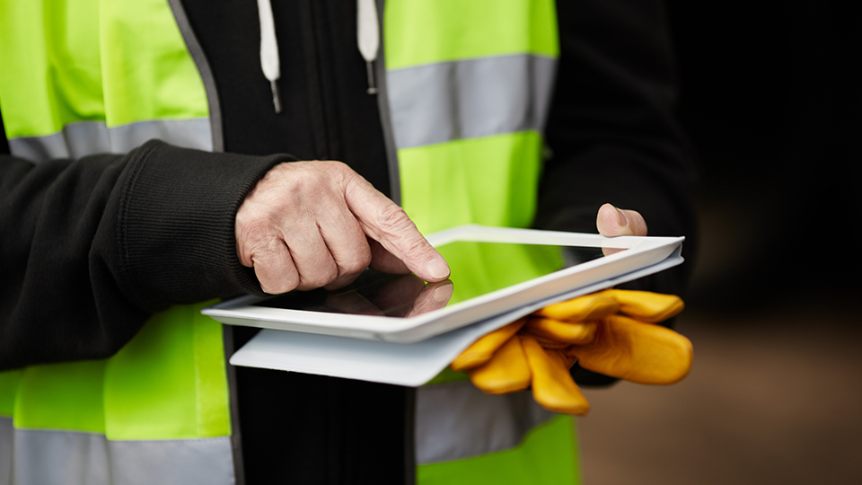 Contractor wearing high vis jacket working on ipad