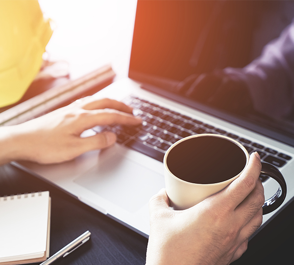 person filling in an online induction on a laptop with a cup of coffee